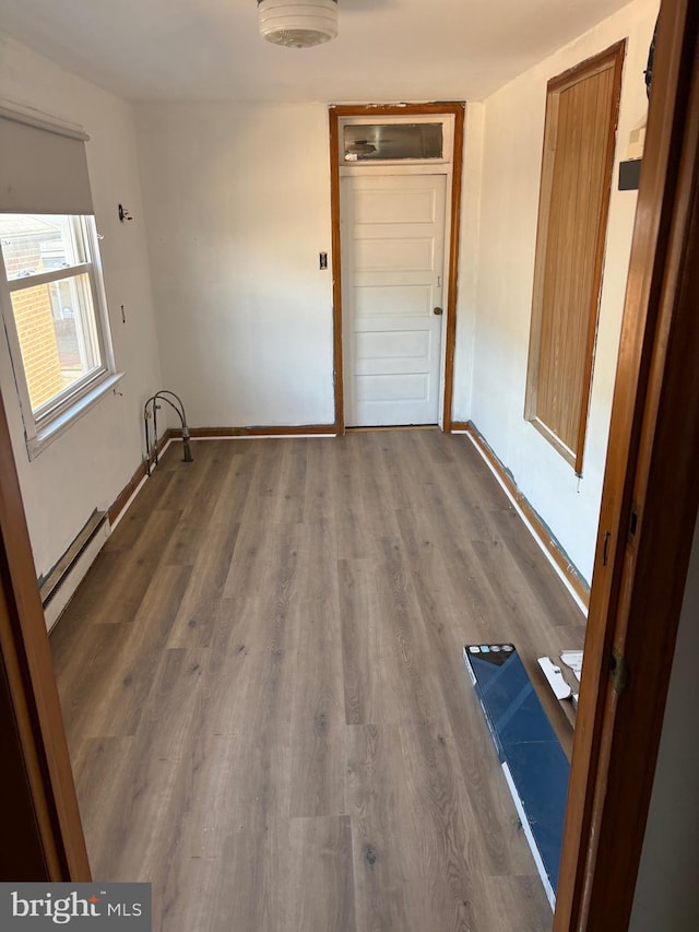 spare room featuring baseboards, baseboard heating, and wood finished floors