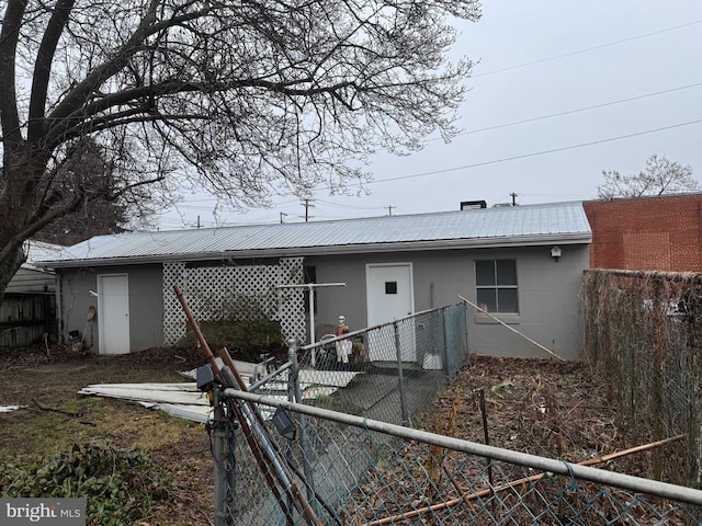 back of property with metal roof, fence private yard, and concrete block siding