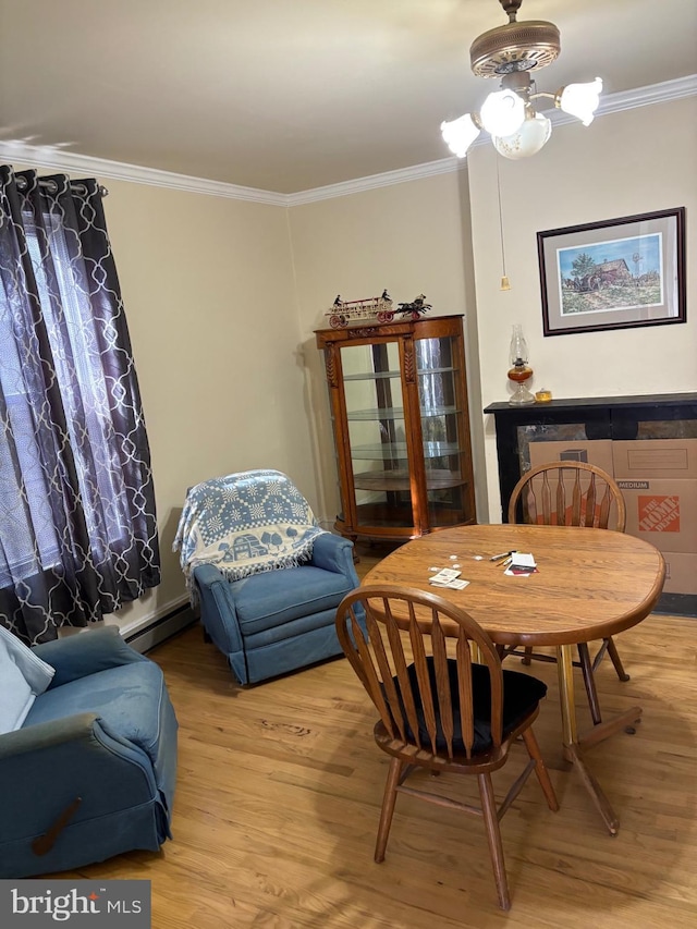 dining area featuring a baseboard heating unit, light wood finished floors, and ornamental molding