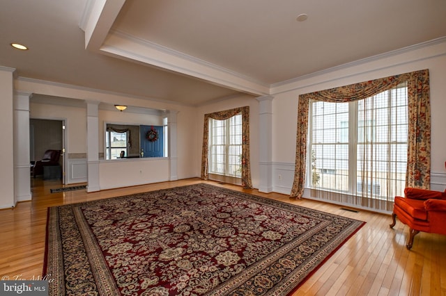 living room featuring ornate columns, light wood-style flooring, and crown molding