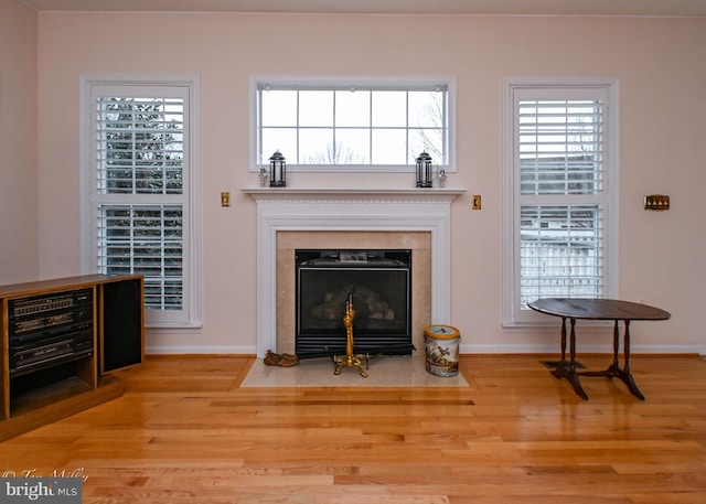 living area with light wood-style floors, a fireplace with flush hearth, and baseboards