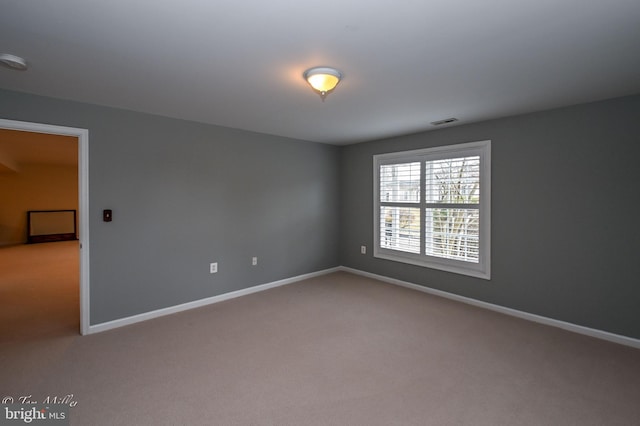 carpeted spare room featuring baseboards and visible vents