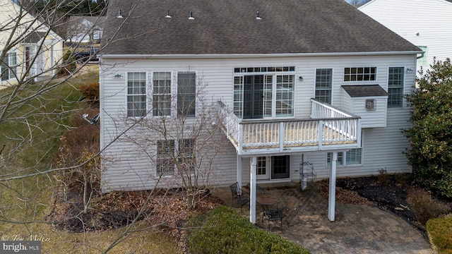 back of house featuring a patio area and roof with shingles