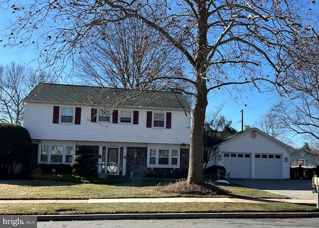 colonial home with a garage, stone siding, driveway, and a front yard