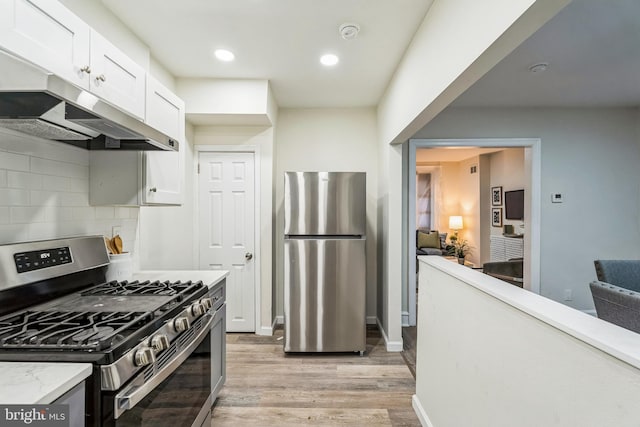 kitchen featuring stainless steel appliances, white cabinetry, tasteful backsplash, and light wood-type flooring