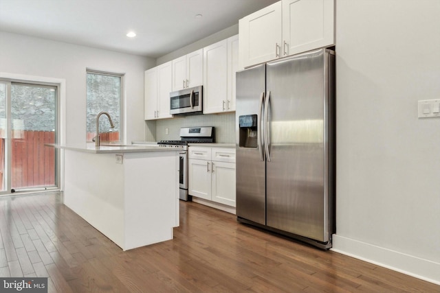 kitchen featuring appliances with stainless steel finishes, white cabinetry, sink, a kitchen island with sink, and dark wood-type flooring