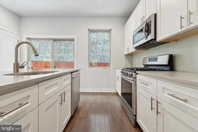 kitchen with sink, backsplash, stainless steel appliances, light stone countertops, and white cabinets