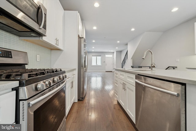 kitchen with sink, dark hardwood / wood-style flooring, white cabinets, stainless steel appliances, and backsplash