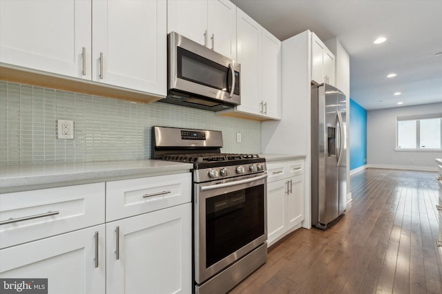 kitchen featuring backsplash, dark hardwood / wood-style floors, white cabinets, and appliances with stainless steel finishes