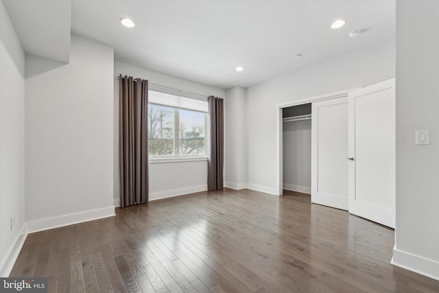 unfurnished bedroom with dark wood-type flooring and a closet