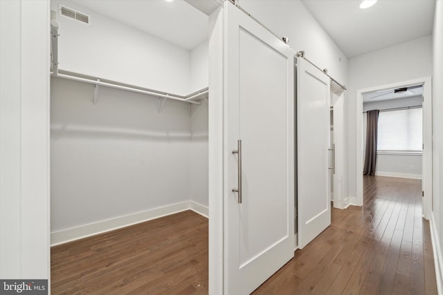 spacious closet with a barn door and dark hardwood / wood-style flooring