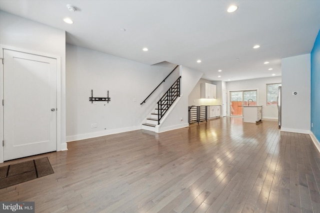 unfurnished living room with sink and hardwood / wood-style floors