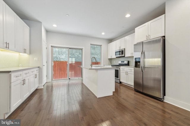 kitchen featuring dark hardwood / wood-style floors, white cabinetry, sink, stainless steel appliances, and a center island with sink