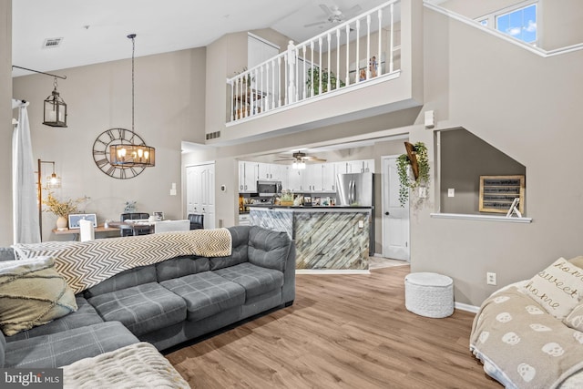 living room featuring ceiling fan with notable chandelier and light hardwood / wood-style floors