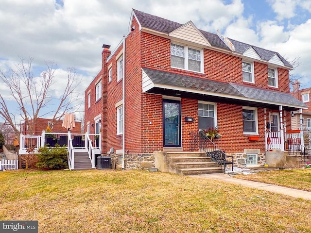 view of front of house with central AC and a front lawn