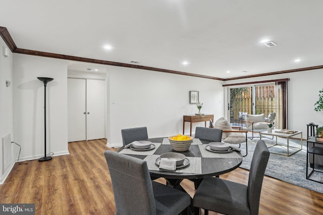 dining area with wood finished floors, visible vents, and crown molding