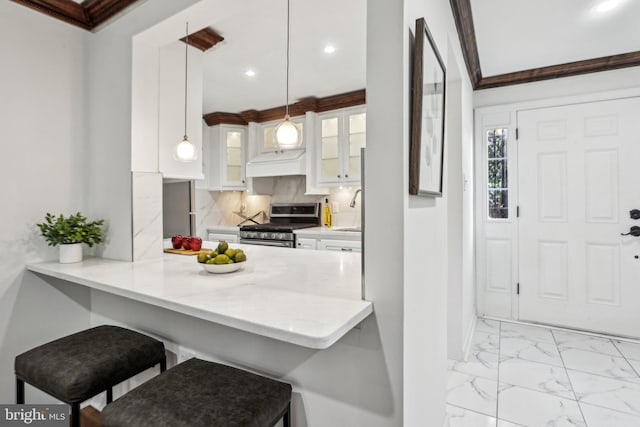 kitchen with glass insert cabinets, light countertops, stainless steel range with gas cooktop, white cabinetry, and pendant lighting