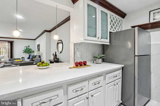 kitchen featuring light stone counters, hanging light fixtures, glass insert cabinets, freestanding refrigerator, and white cabinets