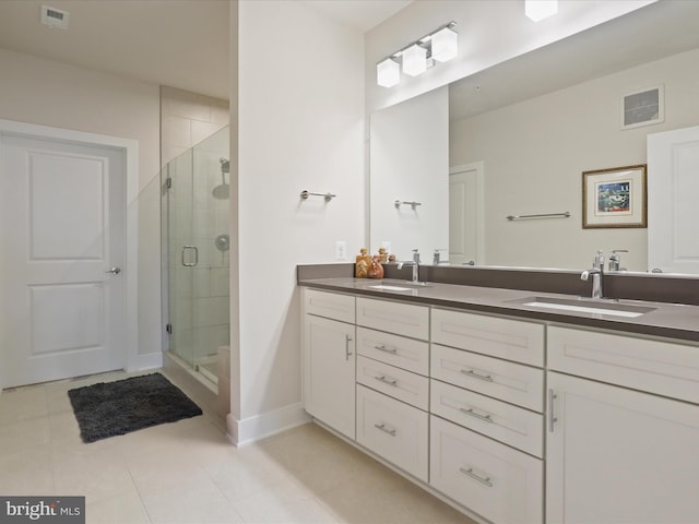 bathroom with a shower with door, vanity, and tile patterned floors