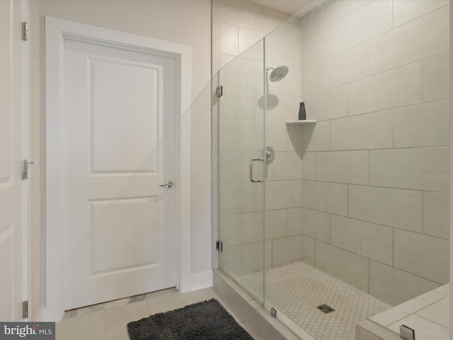 bathroom with a shower with door and tile patterned flooring