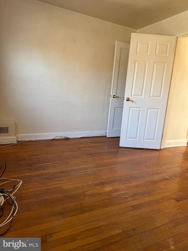 empty room with baseboards and dark wood-type flooring