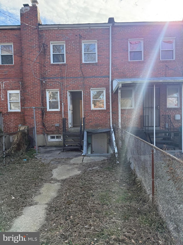 rear view of property featuring fence and brick siding