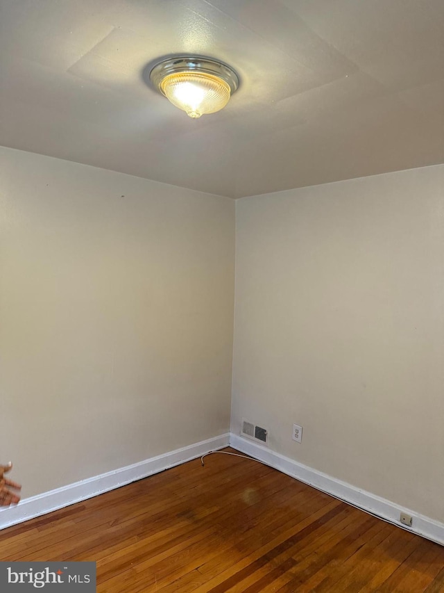 spare room with visible vents, baseboards, and wood finished floors