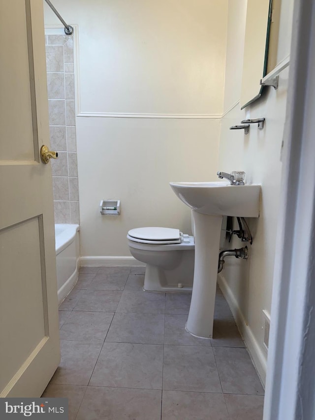 bathroom with washtub / shower combination, tile patterned flooring, baseboards, and toilet