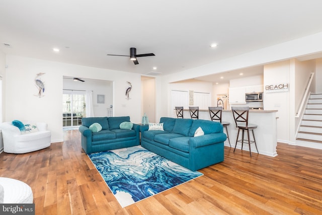 living room with light wood-style flooring, recessed lighting, ceiling fan, and stairway