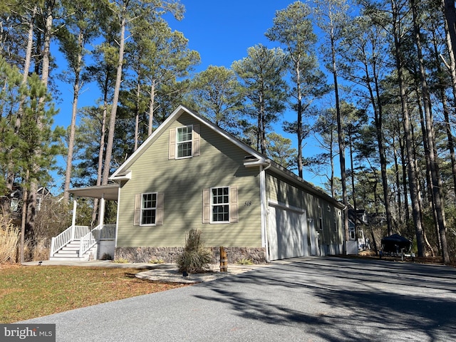 view of side of home featuring covered porch and aphalt driveway