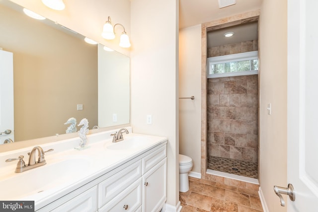 full bath featuring tiled shower, a sink, toilet, and double vanity