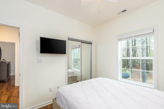 bedroom with a closet, visible vents, baseboards, and wood finished floors