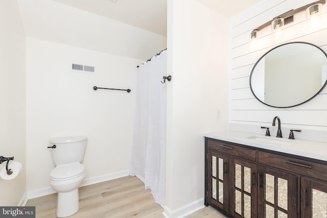 full bath featuring visible vents, toilet, vanity, wood finished floors, and baseboards