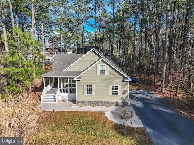 view of front of home with driveway, a front lawn, a porch, and roof with shingles