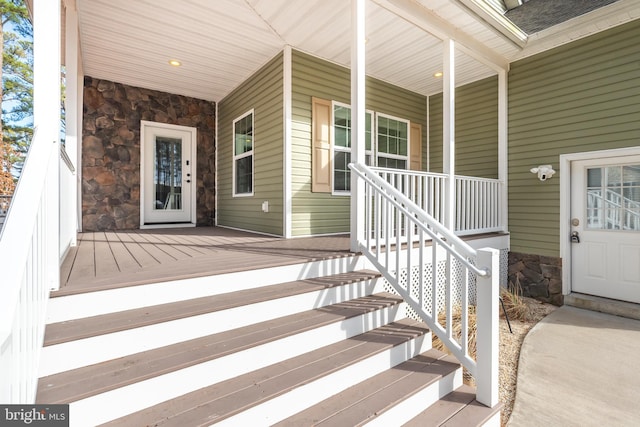 entrance to property with a porch and stone siding