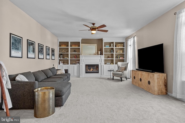 carpeted living area with a ceiling fan and a glass covered fireplace