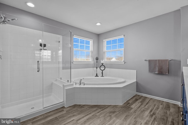 full bath with a stall shower, a garden tub, baseboards, and wood finished floors