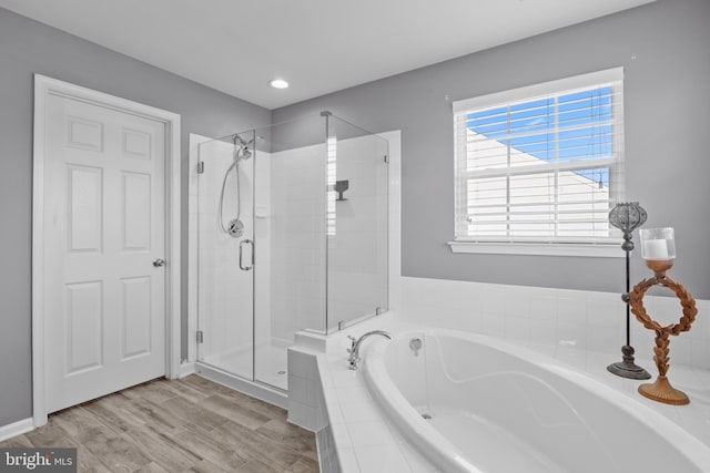 bathroom with a stall shower, wood finished floors, and a bath