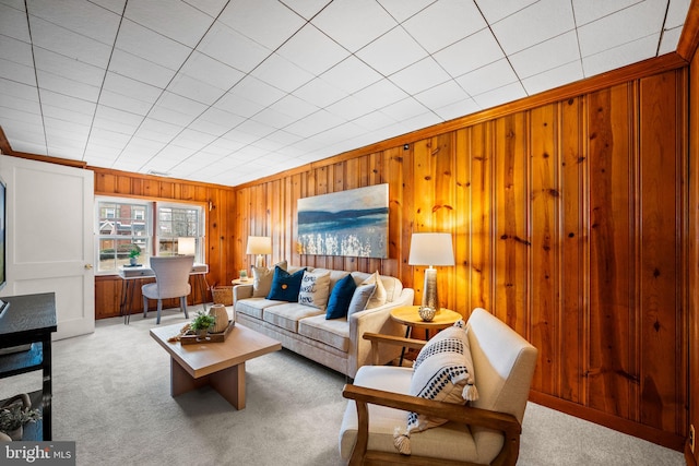 carpeted living room with wooden walls and crown molding