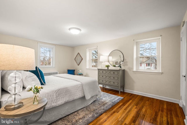 bedroom featuring multiple windows, baseboards, and wood finished floors