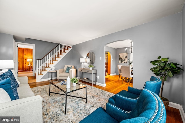 living area featuring arched walkways, stairway, and wood finished floors