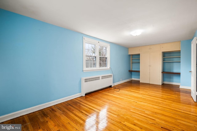 unfurnished bedroom featuring a closet, light wood-type flooring, radiator, and baseboards