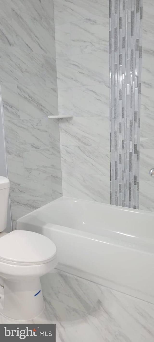 full bath with  shower combination, marble finish floor, and toilet