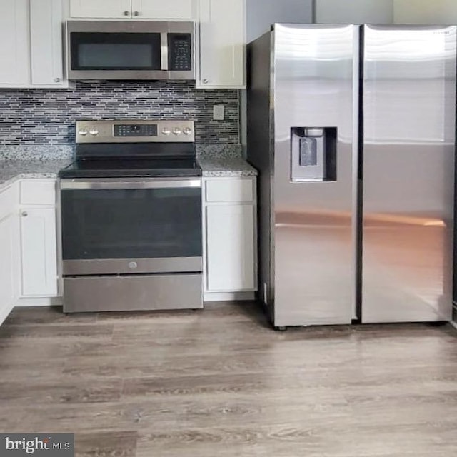 kitchen featuring appliances with stainless steel finishes, light wood-style flooring, white cabinetry, and light stone countertops