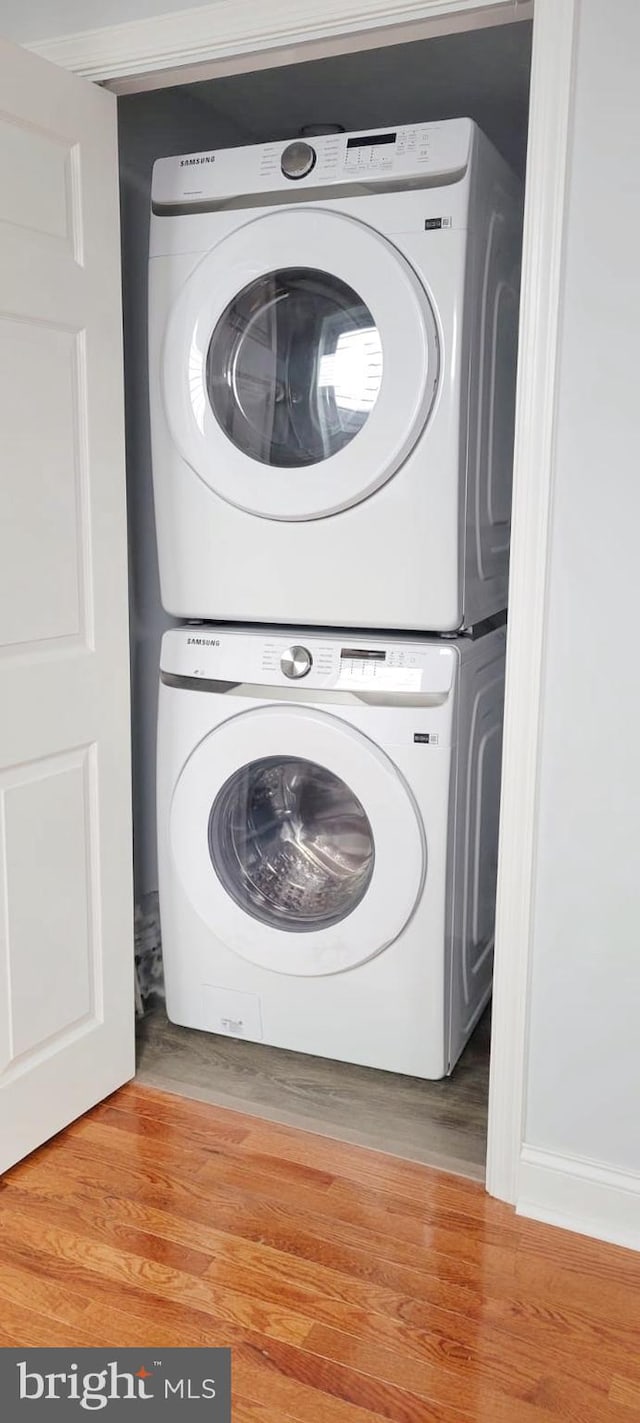 laundry room with laundry area, wood finished floors, and stacked washer and clothes dryer