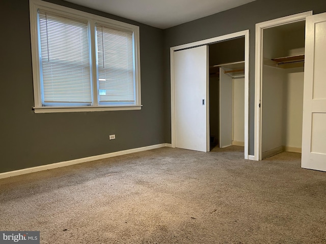 unfurnished bedroom with multiple closets and carpet