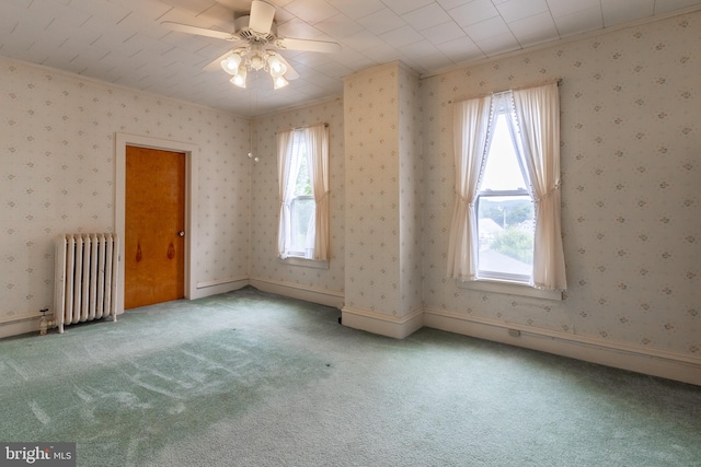 spare room with carpet floors, radiator, ceiling fan, and crown molding