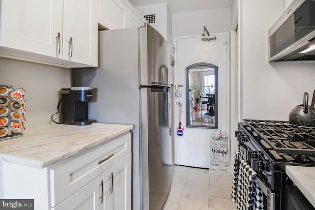 kitchen featuring white cabinetry, appliances with stainless steel finishes, and light stone counters