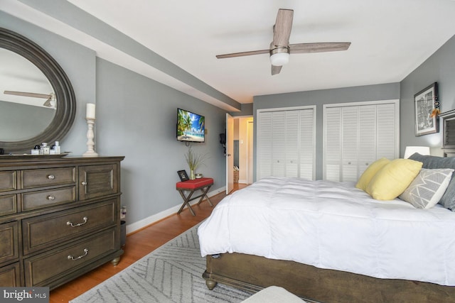 bedroom with two closets, ceiling fan, and wood-type flooring