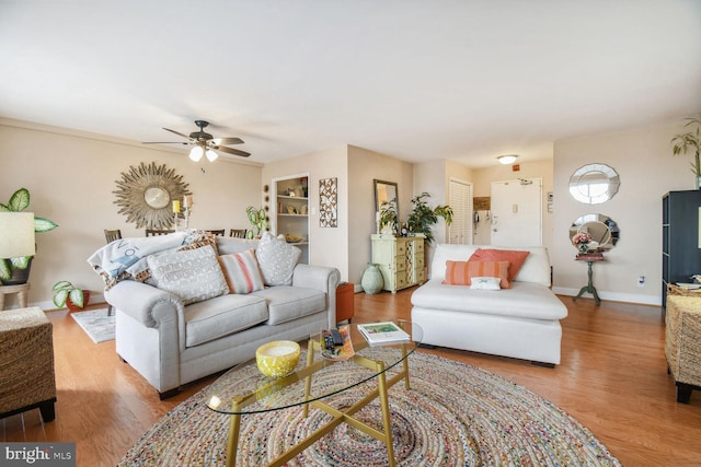 living room with light hardwood / wood-style floors, ceiling fan, and built in features